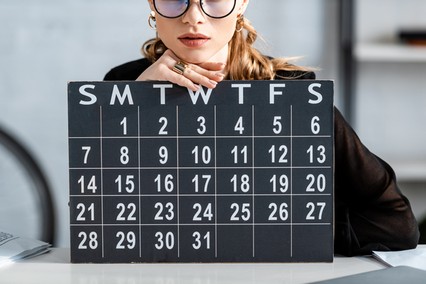 businesswoman in black clothes and glasses holding macroeconomic calendar