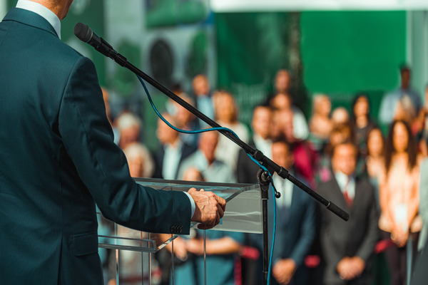 Male Speaker Standing In Front Of Microphones