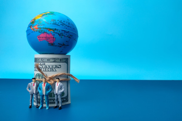 Banknotes,globe and miniature people on a blue background with copy space