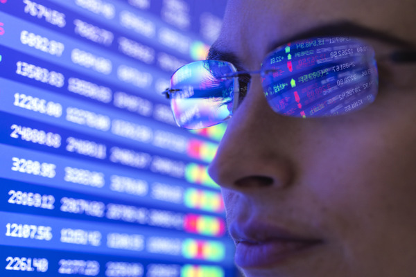 Closeup of a person with stock market numbers reflected in their glasses - ebc