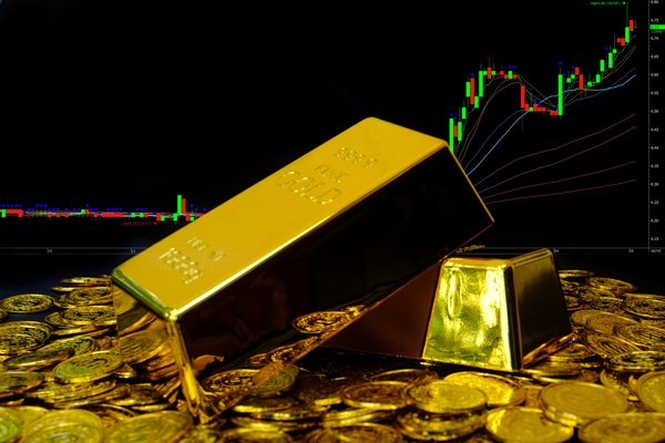 Gold bullion on pile gold coins at trading chart background - ebc